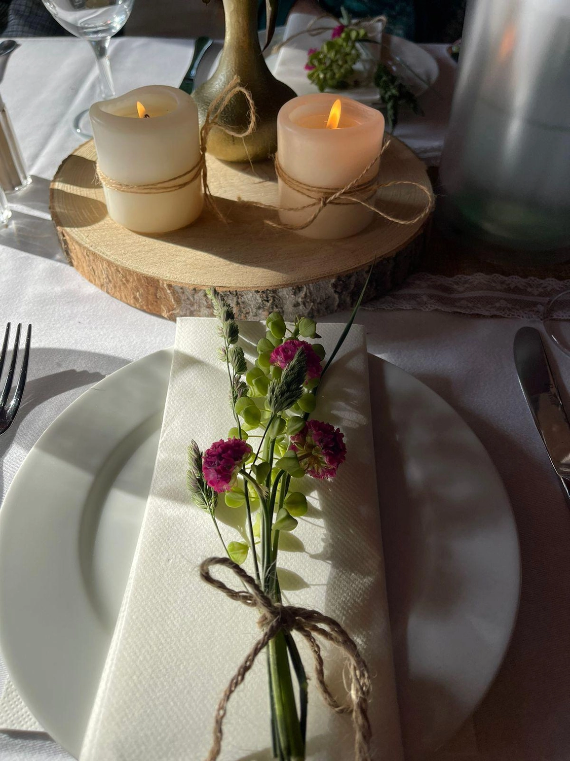 Apfelbaum – Restaurant – Dieses Bild zeigt eine rustikale Tischdekoration für eine Hochzeit oder Veranstaltung mit einer natürlichen Holzscheibe als Mittelpunkt.
