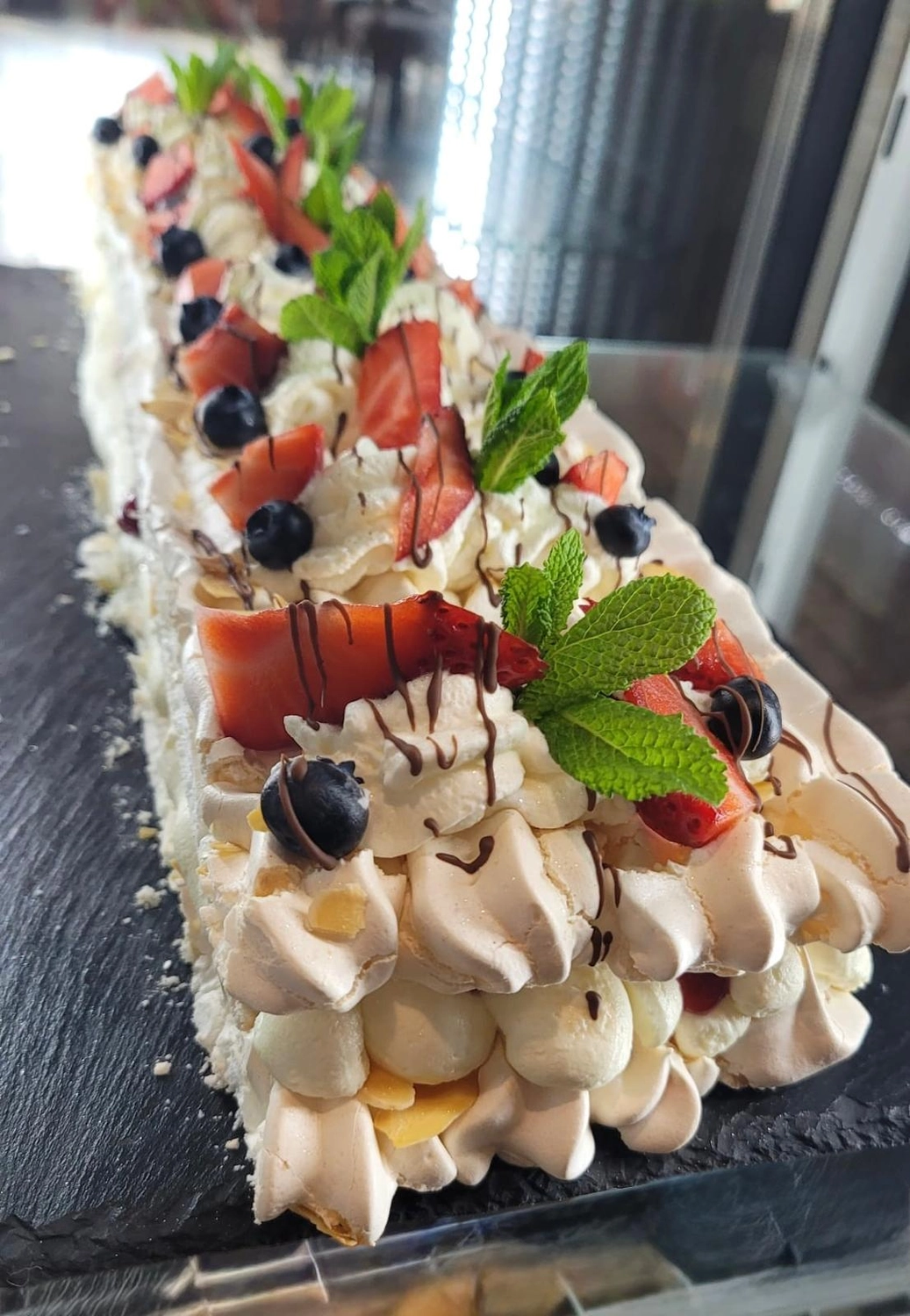 Apfelbaum – Restaurant – Dies ist eine Baiser-Roulade oder Pavlova-Rolle, ein Dessert aus einer leichten, luftigen Baisermasse, geschichtet mit Sahne und frischen Beeren.