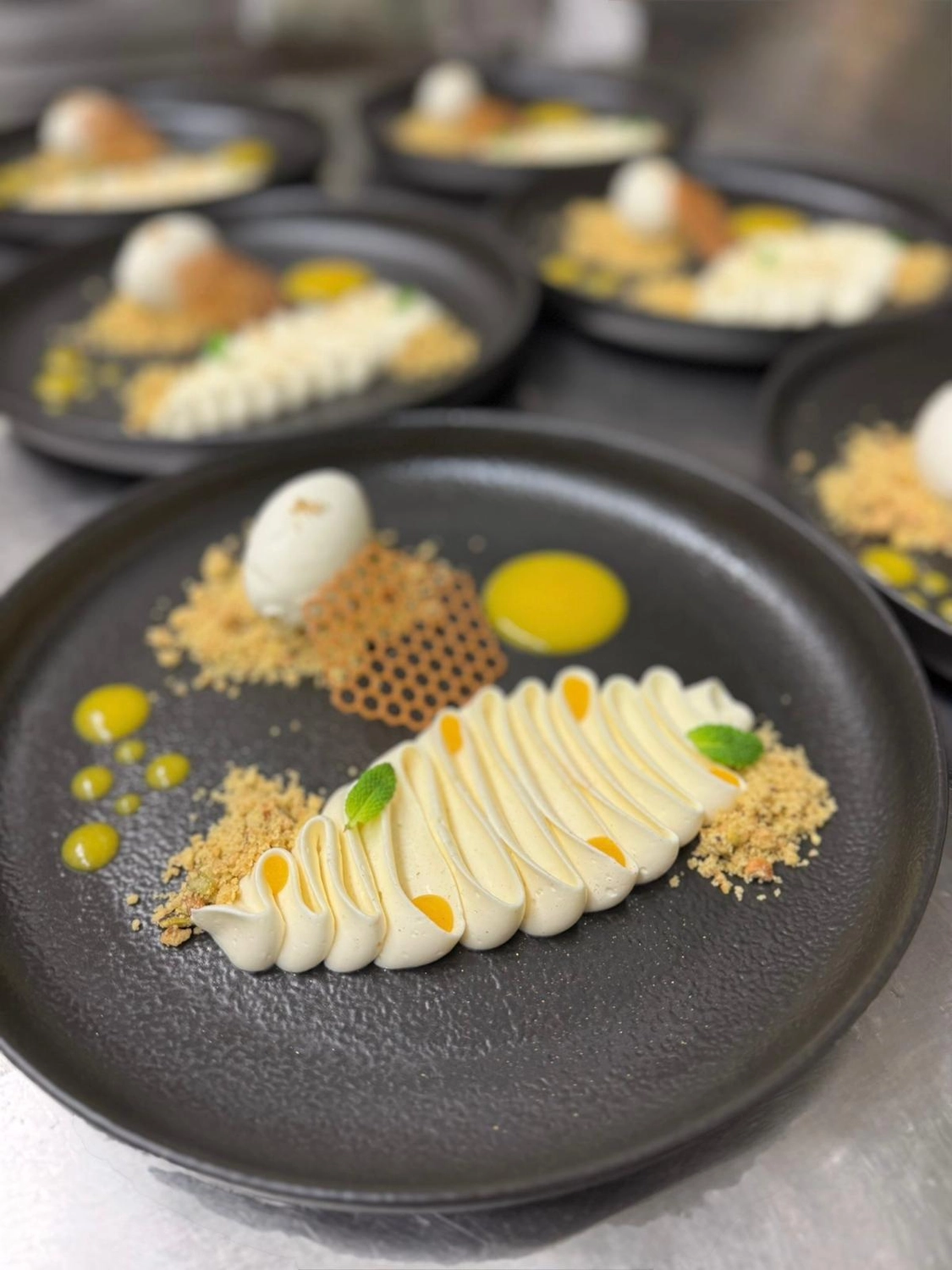 Apfelbaum – Restaurant – Das Bild zeigt einen dekonstruierten Zitronen-Baiser-Kuchen, serviert in einer professionellen Küche.