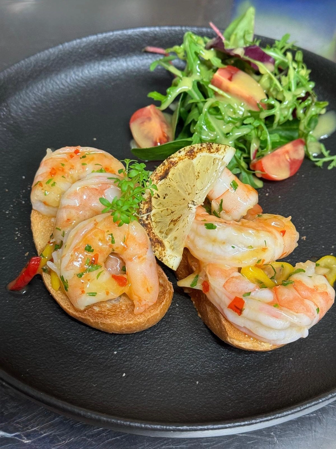 Apfelbaum – Restaurant – Das abgebildete Gericht ist eine Riesengarnelen-Bruschetta, serviert mit einem kleinen Beilagensalat und einer gegrillten Zitronenscheibe.